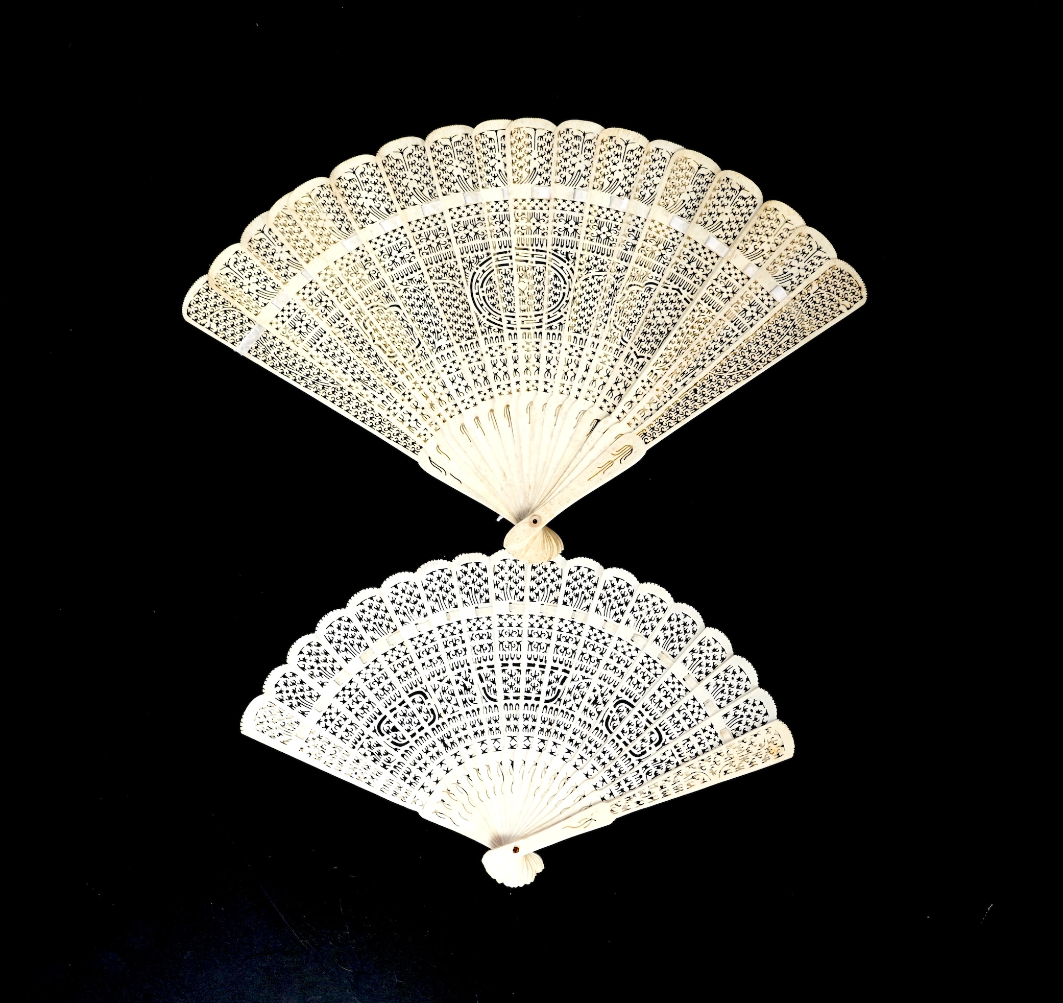A mid 19th century Chinese brisé bone fan with intricate carving and a later smaller similar fan
